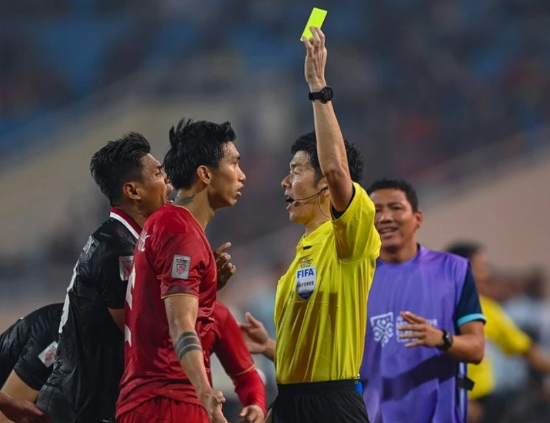 Trọng tài rút thẻ vàng cảnh cáo cầu thủ vi phạm luật thi đấu trên sân.
